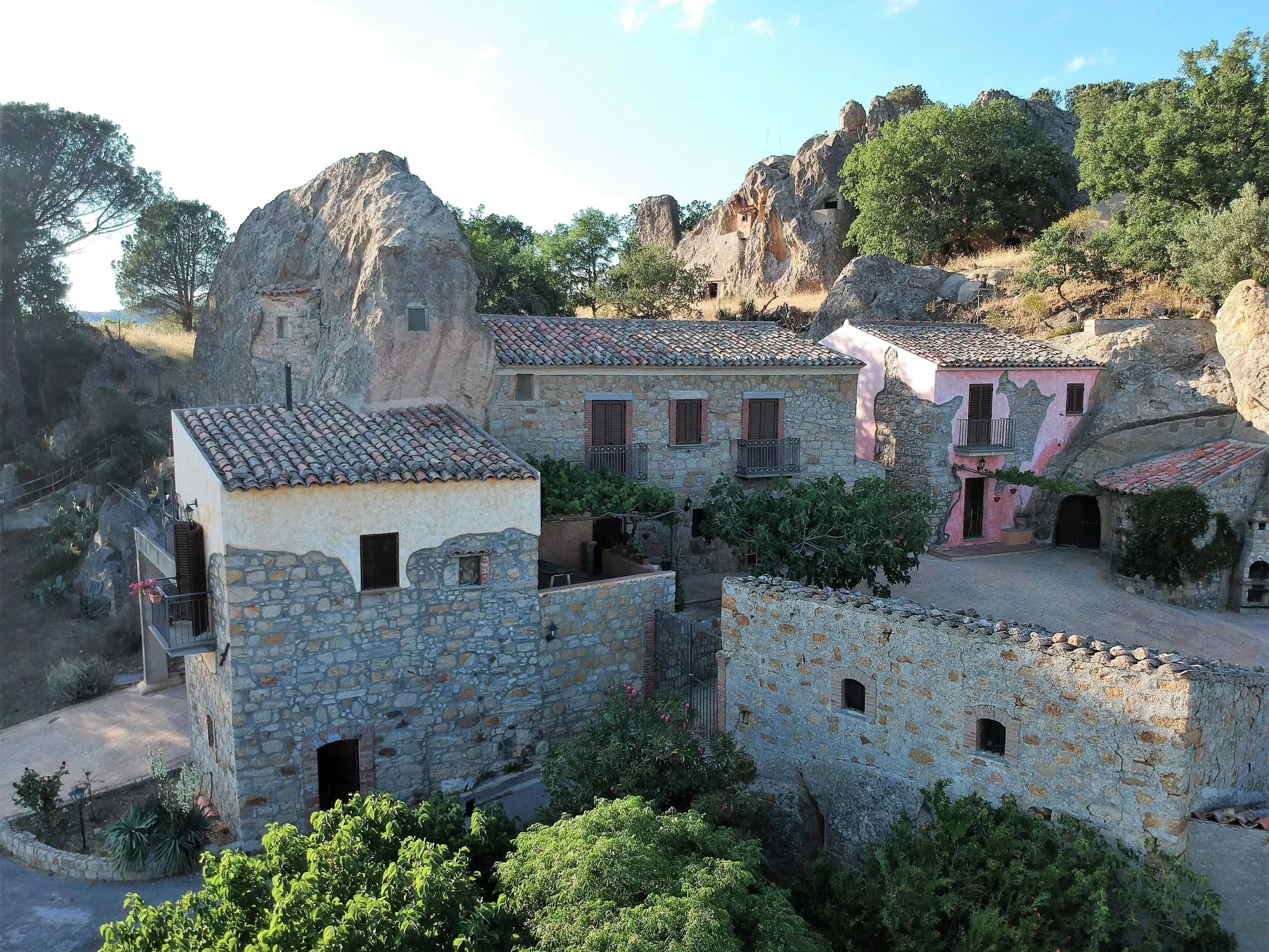 Cortile del complesso visto dall'alto, casa rosa a destra e roccia a sinistra