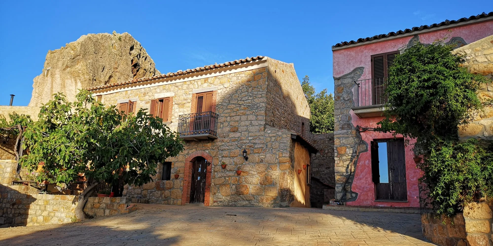 Vista panoramica del cortile della Masseria con insediamenti rupestri, fra la casa colorata di rosa e la roccia scavata