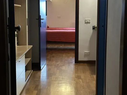 Corridoio con pavimento in legno e porta aperta sulla camera da letto