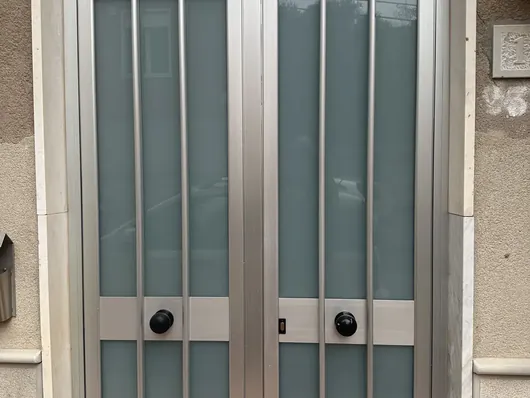 Portone d'ingresso in alluminio con vetri satinati e numero civico sul muro