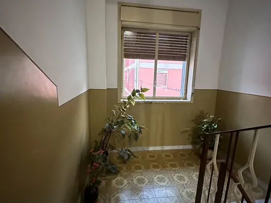 Pianerottolo condominiale con finestra, scala in marmo e pavimento a mattonelle decorate